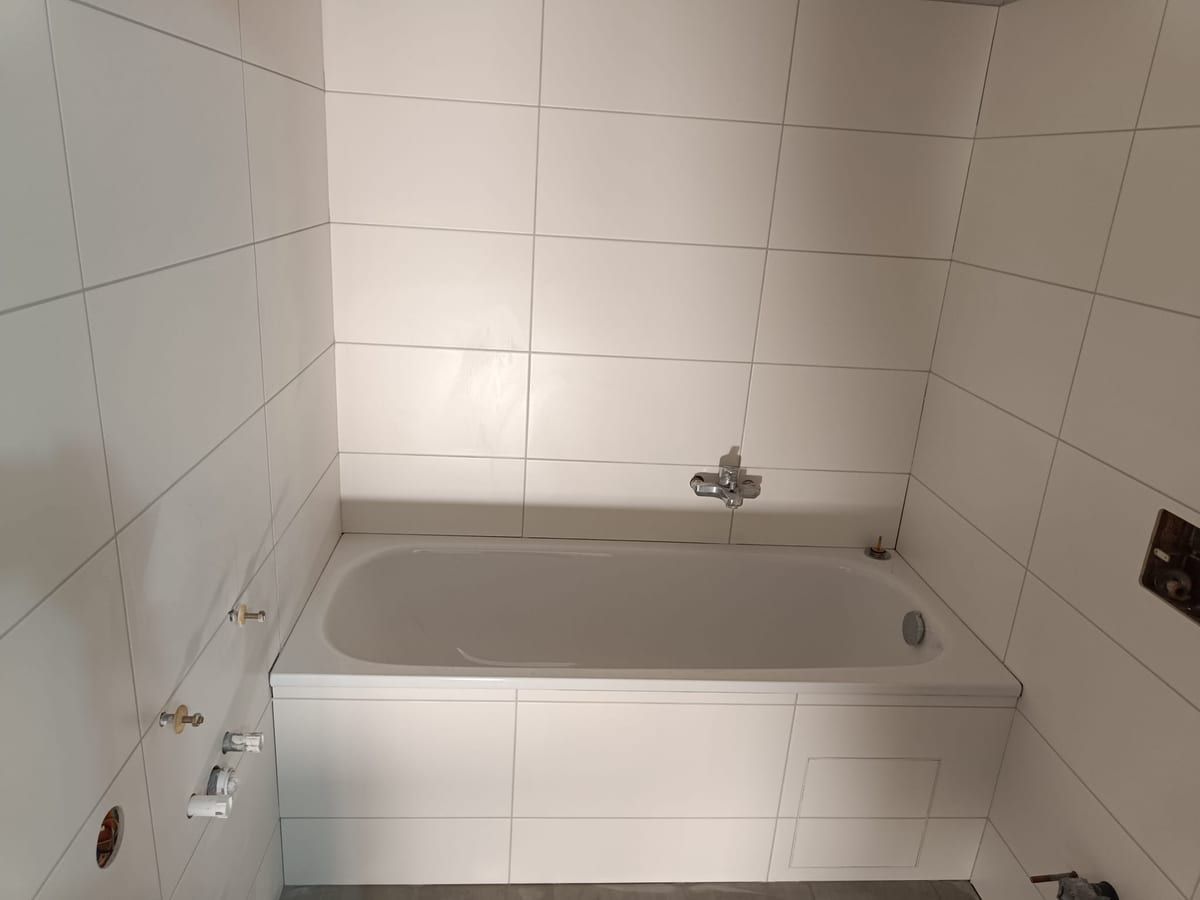 Weiß gefliestes Bad mit Badewanne